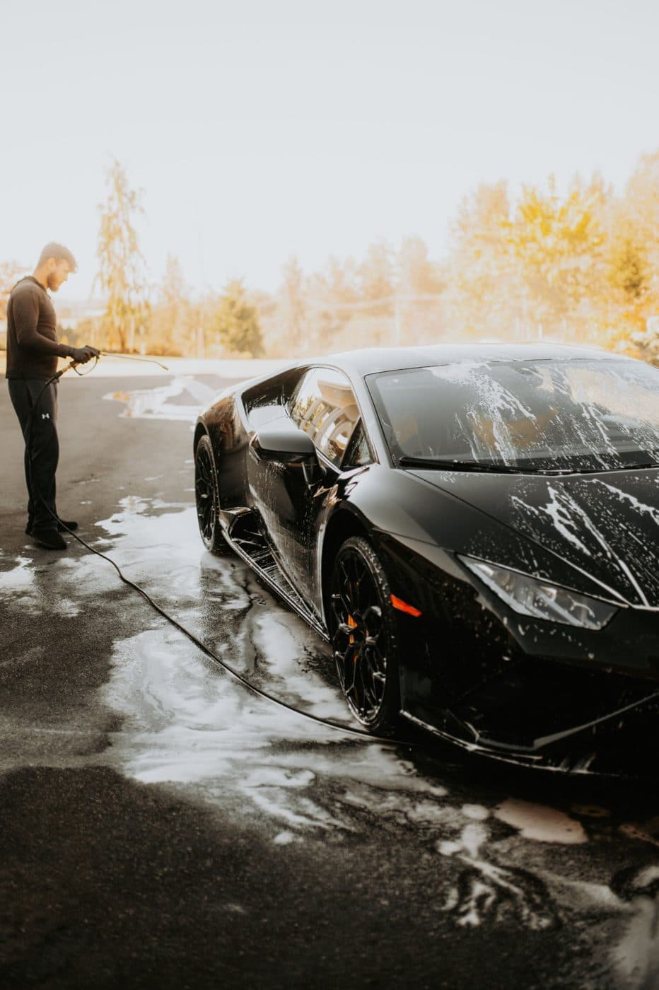 Black supercar being rinsed in a driveway